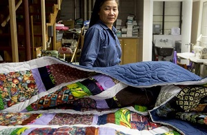 A person looks over a pile of quilts