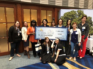 A group of women pose with a large check