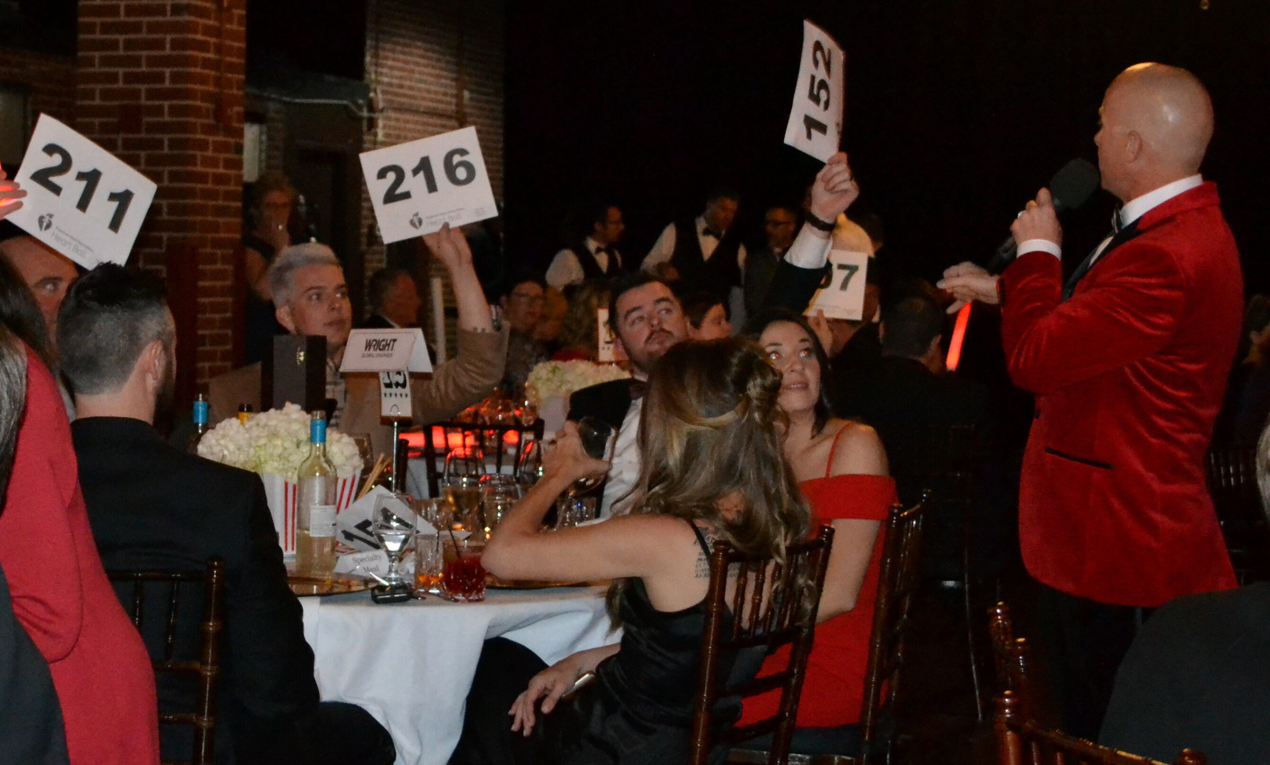 A group of people sitting at a table hold up signs with numbers on them